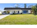 Charming single Gathering home with a well-manicured lawn and a combination stone and blue accent wall at 3560 Middletown St, Port Charlotte, FL 33952