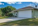 Green house exterior with a white garage door and side yard view at 4695 W Price Blvd, North Port, FL 34286