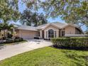 Tan house with a two-car garage and manicured lawn at 487 Summerfield Way, Venice, FL 34292