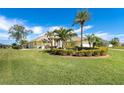 Landscaped yard with a yellow house and palm trees at 49 Perimeter Dr, Englewood, FL 34223
