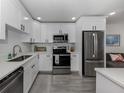 Modern kitchen with white cabinets, stainless steel appliances, and light gray wood-look tile flooring at 525 Manatee Ct # 4, Venice, FL 34285