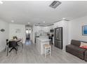 Open-concept kitchen featuring gray wood-look tile, an island, stainless steel appliances, and a dining table at 525 Manatee Ct # 4, Venice, FL 34285