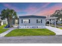 Mobile home exterior with landscaped yard and covered patio at 6401 Floral Ct, North Port, FL 34287