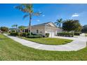 Exterior view of a single-story villa with a white garage door and lush landscaping at 1102 Auburn Cove Cir, Venice, FL 34292