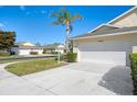 Exterior view of a villa with a white garage door, palm trees, and a paved driveway at 1102 Auburn Cove Cir, Venice, FL 34292