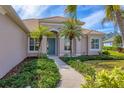 Charming single-Gathering home features a blue front door, lush landscaping, and mature palms at 357 Marsh Creek Rd, Venice, FL 34292