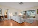 Living room with white sectional sofa, sunroom, wood floors, and mid century modern decor at 407 Degas Dr, Nokomis, FL 34275