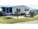 Landscaped mobile home with covered porch and mature plants at 563 Portside Dr, North Port, FL 34287