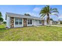 House with gray exterior, stone accents, and a palm tree in the front yard at 6232 Drucker Cir, Port Charlotte, FL 33981