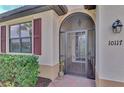 Front entrance with decorative screen door, red shutters, and brick walkway at 10117 Colubrina Dr, Venice, FL 34293