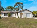 Inviting single-Gathering home showcasing lush lawn, arched entry, and attached garage at 1023 Hope St, Venice, FL 34285