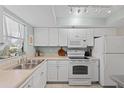 Bright kitchen featuring white appliances and ample counter space plus a window with views of the yard at 104 Capri Isles Blvd # 107, Venice, FL 34292