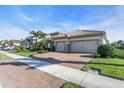 Charming home with a two-car garage, brick driveway, manicured lawn, and lush landscaping at 11903 Alessandro Ln, Venice, FL 34293