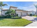 Charming home with a two-car garage, brick driveway, manicured lawn, and lush landscaping at 11903 Alessandro Ln, Venice, FL 34293