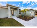 Front entry of a light green house with a porch and landscaping at 12385 Prudential Ave, Port Charlotte, FL 33981