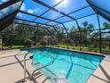 The pool is screened in and boasts clear blue water with a pool-side deck under a sunny sky at 1773 Hudson St, Englewood, FL 34223