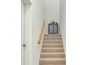 Carpeted staircase with wooden handrail, complemented by a cabinet at the top, adding a touch of elegance at 23194 Banbury Way # 202, Venice, FL 34293