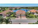 Aerial view of a home with a two-car garage, brick driveway, and community lake at 24065 Canterwood Way, Venice, FL 34293