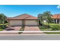 Beautiful home featuring a red tile roof, two-car garage, brick driveway, and meticulously landscaped yard at 24065 Canterwood Way, Venice, FL 34293