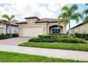 Inviting home features terracotta roof, 2-car garage, paver driveway, and manicured landscaping at 24229 Spartina Dr, Venice, FL 34293