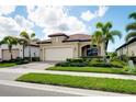 Beautiful, single-story home featuring a red tile roof, a two-car garage, and lush, manicured landscaping at 24229 Spartina Dr, Venice, FL 34293