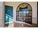 Cozy front porch with a teal front door, a window with curtains, and a wooden bench at 302 Woodingham Ct, Venice, FL 34292