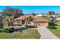 Beautiful single-story home with lush landscaping, a tile roof, and an attached two-car garage at 389 Eden Dr, Englewood, FL 34223