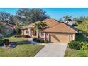 Well-manicured front lawn and mature trees frame this home with a tile roof and two-car garage at 389 Eden Dr, Englewood, FL 34223