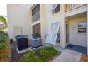 Exterior view of condo with white trim, light-colored siding, AC Unit, and small landscaping at 435 Cerromar Ln # 328, Venice, FL 34293