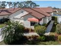 Beautiful home with red tile roof, white stucco, mature landscaping, and close proximity to neighborhood lake at 4951 Summertree Rd, Venice, FL 34293