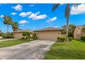 Inviting villa featuring a well-maintained lawn, mature palm trees, and a convenient two-car garage at 7145 Lakeside Dr, Sarasota, FL 34243