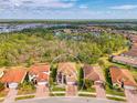 Aerial view of home with tile roof and brick driveway, near a lake, surrounded by lush greenery at 12410 Cinqueterre Dr, Venice, FL 34293