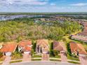 A picturesque aerial view of a neighborhood with lush green trees, lake and tile-roofed homes at 12410 Cinqueterre Dr, Venice, FL 34293