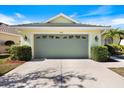 Garage front view featuring manicured landscaping, a neutral driveway, and carriage house doors with decorative windows at 1298 Highland Greens Dr, Venice, FL 34285