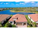An aerial view shows the home's tile roof and lake view with mature trees and tropical landscaping at 13730 Vancanza, Venice, FL 34293