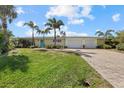 Charming home with a manicured lawn, palm trees, and a brick driveway leading to the attached two car garage at 424 Shade Ter, Venice, FL 34293