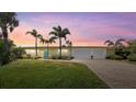 Beautiful home at sunset with a manicured lawn, mature palms, and an attached two-car garage at 424 Shade Ter, Venice, FL 34293