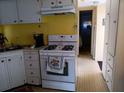 Functional kitchen with a white gas range, bright yellow walls, and ample cabinet space at 718 S Green Cir, Venice, FL 34285