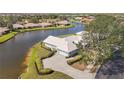 Expansive waterfront property featuring a well-maintained home with a paved driveway and lush landscaping at 803 Carnoustie Dr, Venice, FL 34293