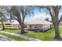 Beautifully maintained single-story home with mature trees, lush lawn, and manicured shrubbery at 803 Carnoustie Dr, Venice, FL 34293