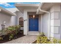 Inviting front entrance featuring a bright blue door, decorative window, and manicured landscaping at 803 Carnoustie Dr, Venice, FL 34293