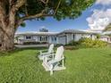 Landscaped front yard featuring two Adirondack chairs, green grass, and a view of the single-story home at 17 Brentwood Ln, Englewood, FL 34223