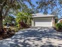 Beautiful home showcasing a well-maintained driveway, complemented by verdant landscaping and mature trees at 564 Meadow Sweet Cir, Osprey, FL 34229