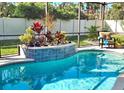 Screened-in pool featuring colorful plantings and a relaxing chair next to the water at 612 Poinsettia Dr, Venice, FL 34285