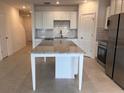 Bright kitchen featuring white cabinets, subway tile backsplash, stainless steel appliances and a large center island at 10719 Ironwood Tree Way, San Antonio, FL 33576