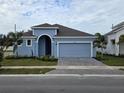 Newly constructed light blue home with a two-car garage and landscaped front yard at 9593 Vibrant Lane, Venice, FL 34292