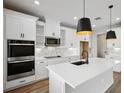 Modern kitchen with white cabinets, white quartz countertops, and stainless steel appliances at 101 Runaway Field Ave, Nokomis, FL 34275