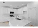 Modern kitchen boasts white cabinets, stainless steel appliances, and a large island with a sink at 9572 Vibrant Lane, Venice, FL 34292