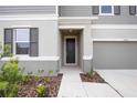 Front entrance with dark gray door and walkway at 37488 Williamette Way, Zephyrhills, FL 33540