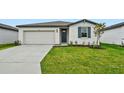 Single-story home with a white exterior, two-car garage, and landscaped lawn at 7760 Gilchrist Springs Dr, Parrish, FL 34219